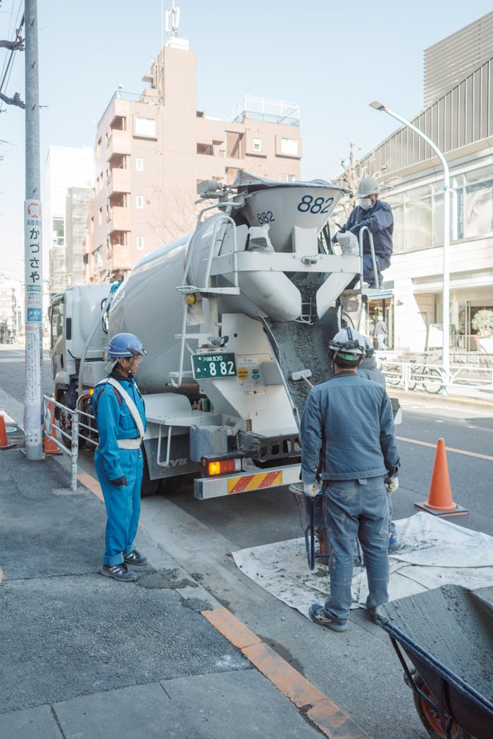 Construction workers operate a cement truck on a street in Shibuya, Tokyo, Japan, showcasing urban development.