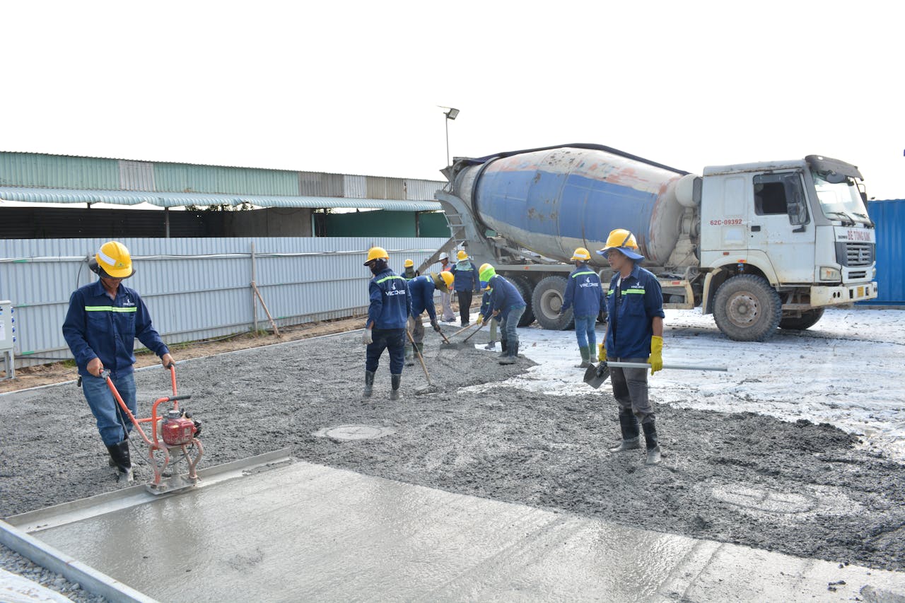 Team of workers pouring cement from a mixer truck on a construction site, ensuring proper leveling.